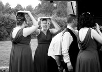 A candid photo of a bridesmaid laughing as she shelters from the rain holding a dinner plate over her head