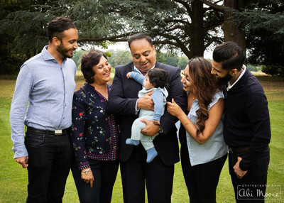 Grandparents, parents and uncle all smile at a baby boy