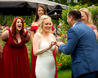 Bridesmaid laughs as bride and groom share a fun moment during their wedding ring exchange