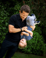 A dad holds his pre-school-aged son upside-down while he gigles