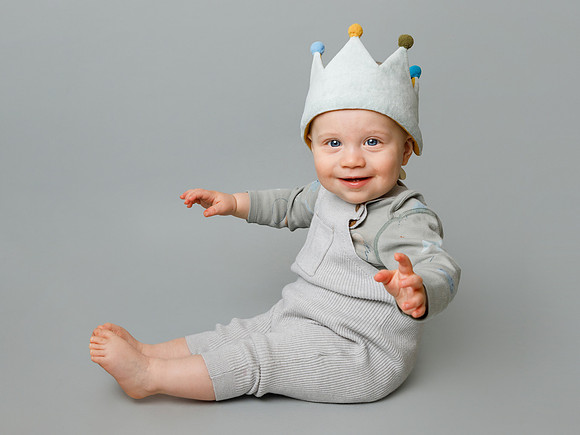 One year old boy wearing a birthday crown in a photo studio