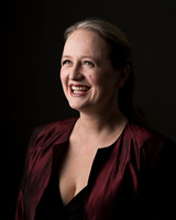 A dramatically lit photo of a woman smiling at someone off-camera