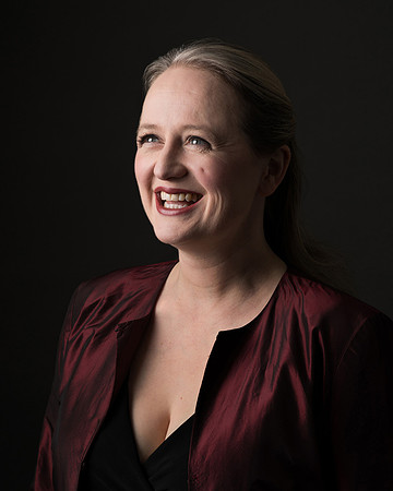 A dramatically lit photo of a woman smiling at someone off-camera