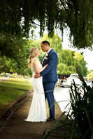 A bride and groom hold each other under a weeping willow alnogside the Thames at Windsor's Oakley Court