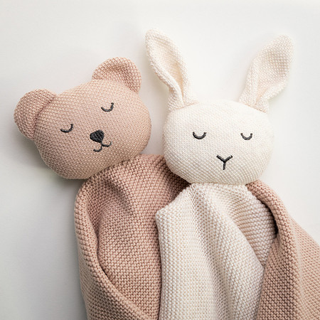 Two knitted animal toys wrapped as though they are hugging