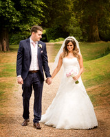 A groom smiles at his bride as they walk in the grounds of Windsor's Oakley Court hotel
