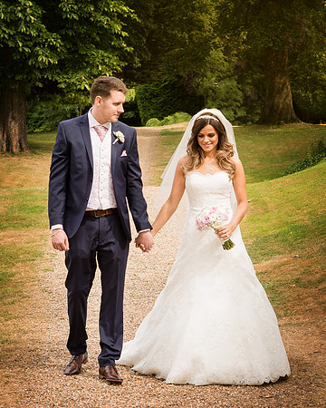 A groom smiles at his bride as they walk in the grounds of Windsor's Oakley Court hotel