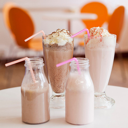 Milkshakes photographed on a table with orange chairs in the background