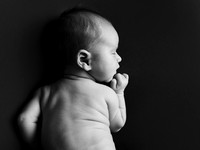 black & white high contrast image of a baby laying on his front with head turned to the side, shot in black and white