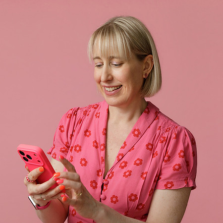 Abi Moore - brand photography and small business marketing expert - seated on an armchair with a laptop on her lap