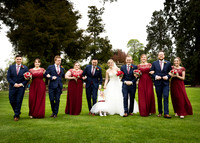 A bridal party walk arm-in-arm through the grounds of Oakley Court