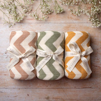 Three chevron blankets from Isla & Fraser phtoographed in a row on wood with gypsophilia