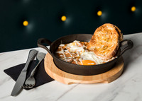 A breakfast skillet photographed on marble tabletop with knife. fork and napkin