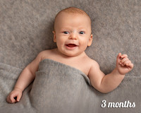 Three month old baby smiles at the camera