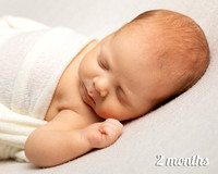Two month old baby sleeps on his back with his head turned to the side