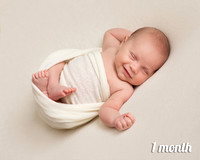 One month old baby lays swaddled on his back smiling in his sleep