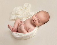Sleeping newborn baby wrapped in cream blanket