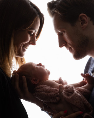 Backlit semi-silhouette of a baby looking up at her parents