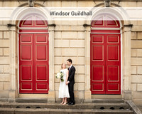 A wedding couple look at each other whilst holding hands framed by the red doors of Windsor's Guildhall