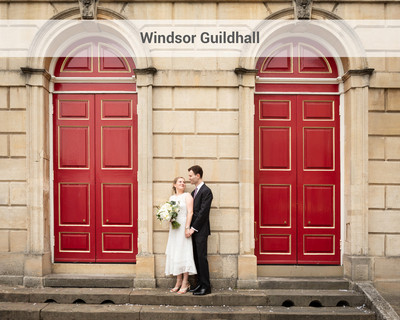 Wedding couple stand by the big red doors of Windsor's Guildhall