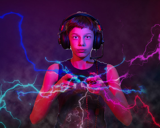 Enhanced colourful photo of teen boy playing games console with lightning and smoke coming from his controller