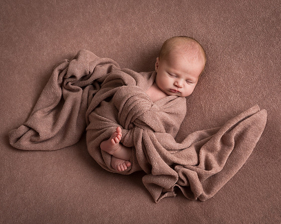 Award-winning photograph of baby girl wrapped in pink on matching background