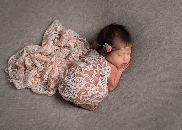 Relaxed, natural sleepy baby girl during photo shoot with grey and pink colour theme