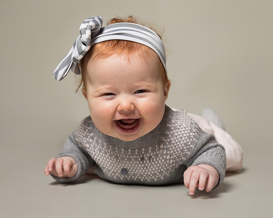 Cute baby girl lying on front with huge smile
