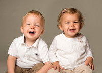 Twin boy and girl giggle whilst being photographed in a studio setting
