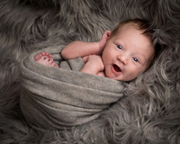 Smiley awake baby smiles at camera during newborn photo shoot