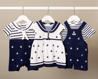 Three sailor outfits for infants hung on a white rail