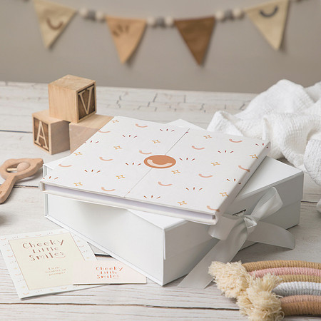 Branding photoshoot image of a baby journal stacked with gift box and baby items