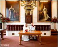 A couple sign the register during their Windsor Guildhall wedding ceremony, flanked by royal portraits