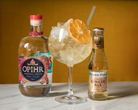 A photo of Opihr gin and tonic aside a gin glass against a yellow background