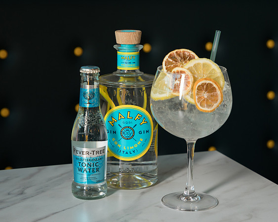 Gin and tonic beside the bottles that are ingredients