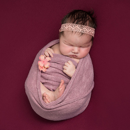 Newborn baby girl photographed on a pink background