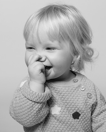 Toddler girl sucks her thumb and smiles
