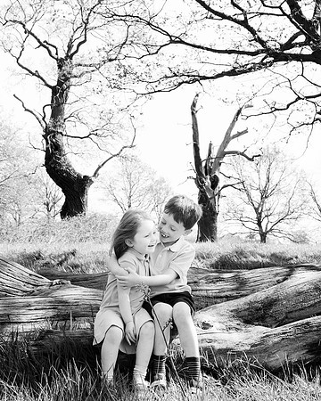Brother and sister giggle together during outdoor professional photoshoot