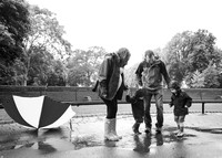Family jump in puddles during rainy maternity photo session