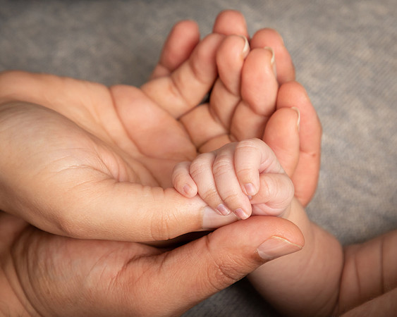 Close up of baby hand holding onto it's parents' fingers