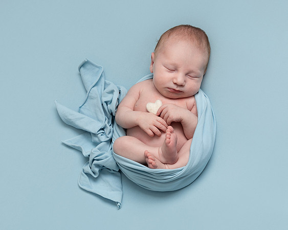 Newborn baby boy wrapped in blue and holding a heart - baby photography in Windsor