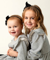 Two young sisters dressed in matching outfits in a close-up studio photograph