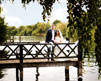 A wedding couple pose for a wedding photo on the jetty in the grounds of Oakley Court