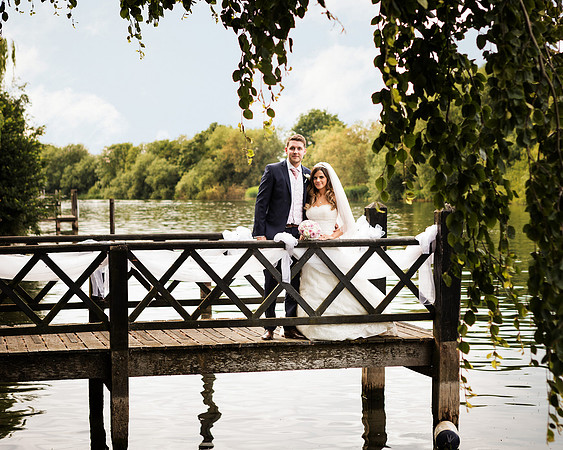 A wedding couple pose for a wedding photo on the jetty in the grounds of Oakley Court