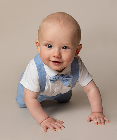 Baby smiles and crawls towards camera in studio photoshoot