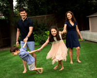 Family hold hands, walk and play together in their garden