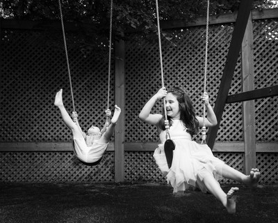 children photographed in their garden having fun on swings