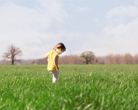 Young girl walks in a meadow in Windsor Great Park in bright sunlight