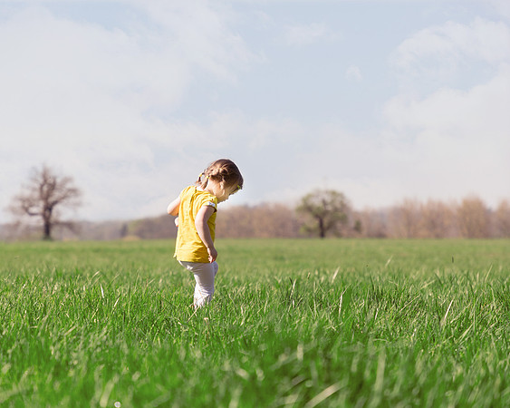 Young girl walks in a meadow in Windsor Great Park in bright sunlight