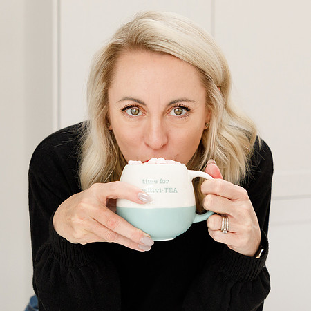 Lady leaning forward drinking coffee looking directly at the camera